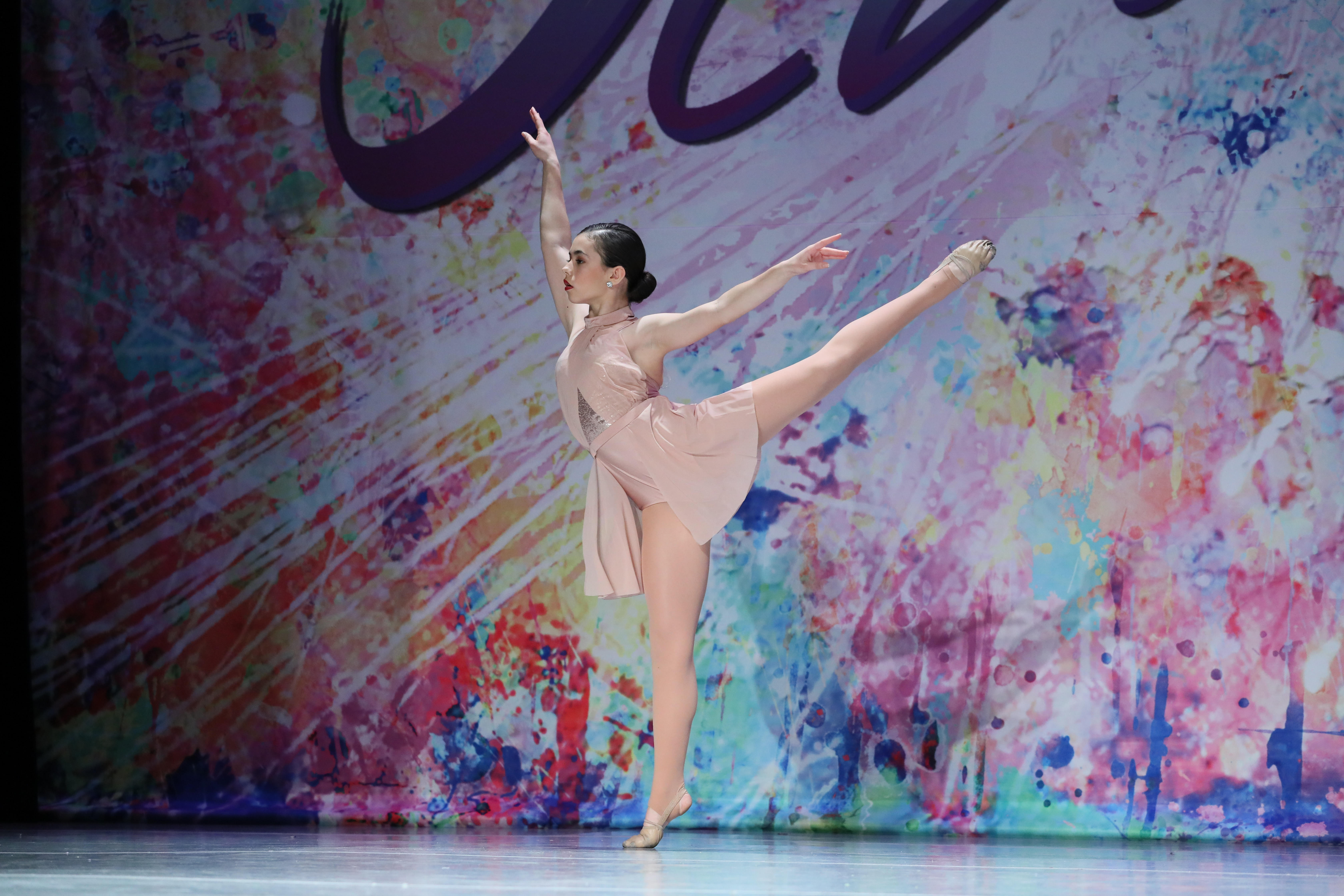 A dancer in a pale pink costume extending her leg during a solo