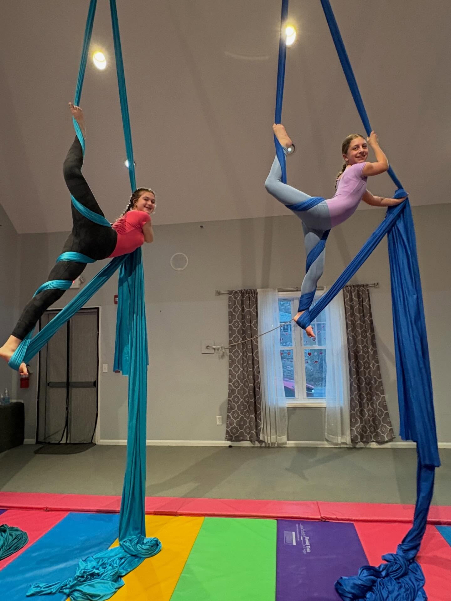 Two students exploring new poses on aerial silks